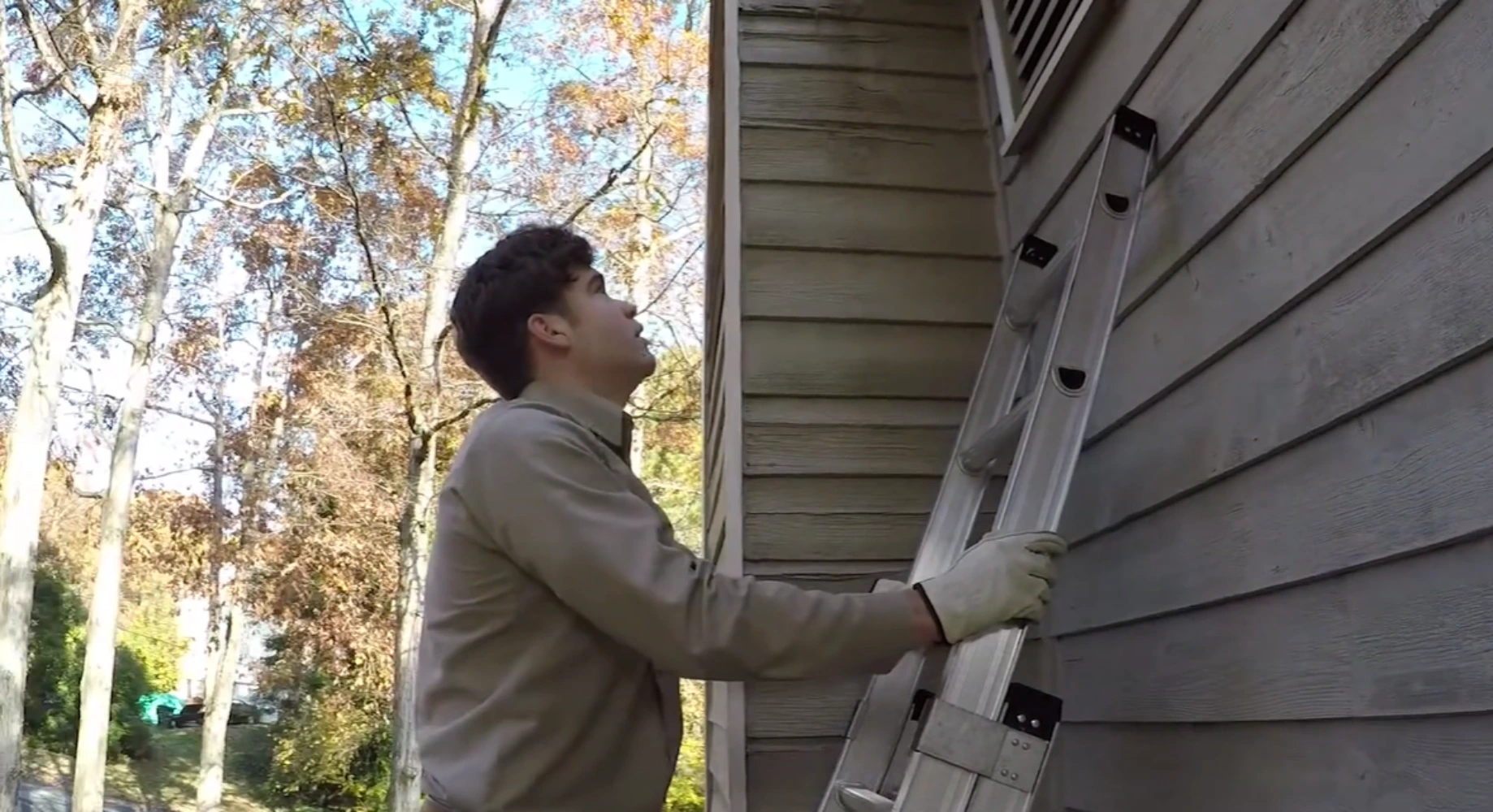 Licensed bat removal inspector checking ridge vent end cap gap on Troy MI home exterior